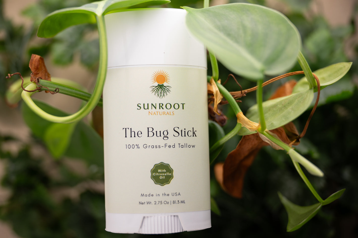 Alt Text:
Sunroot The Bug Stick insect repellent displayed among green foliage outdoors.